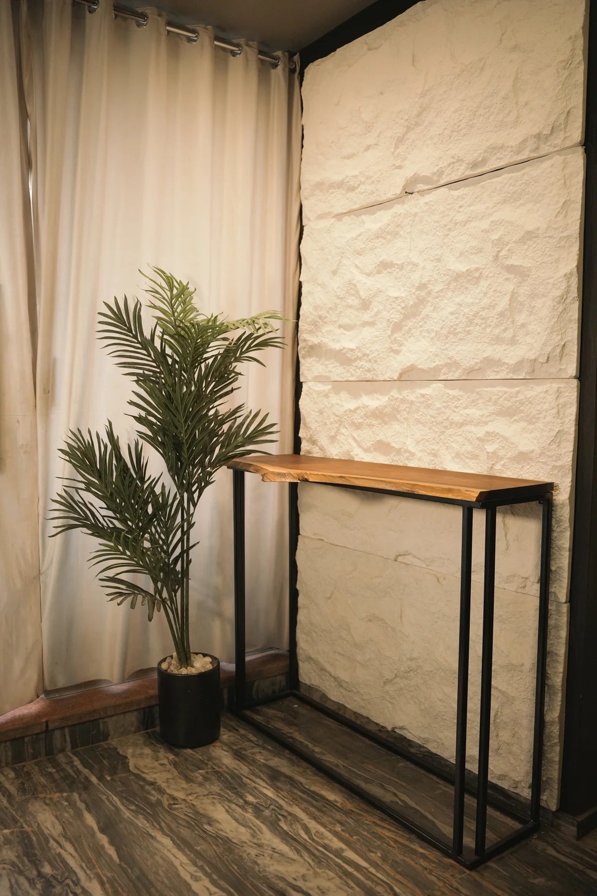 Console table with a plant against a textured wall and curtain