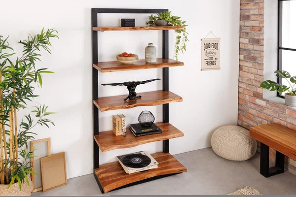 Wooden shelf with decorative items in a room with plants and a brick wall.