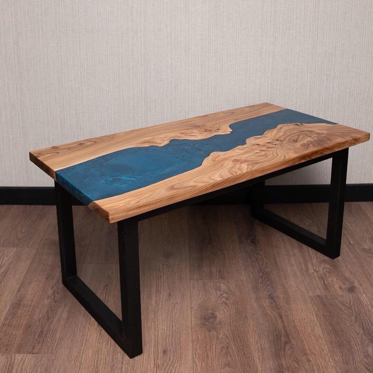 Wooden table with blue resin inlay on a wooden floor